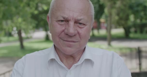 Portrét šťastného staršího muže v košili při pohledu na kameru sebevědomě venku — Stock video