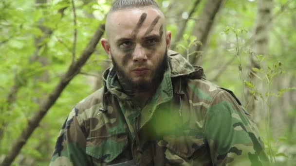 Portret wściekłego wojownika w kamuflażu z bronią występującą w lesie — Wideo stockowe