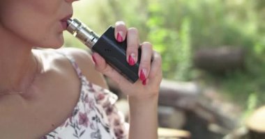 Bir kadının e-sigara içişini yakından görmek ve yaz doğasında kameraya nefes vermek.