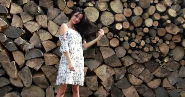 Élégante dame en robe légère pose avec sourire sur fond de bois — Video