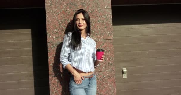 Szczęśliwa dziewczyna stoi z filiżanką herbaty w garażach na parkingu i raduje — Wideo stockowe