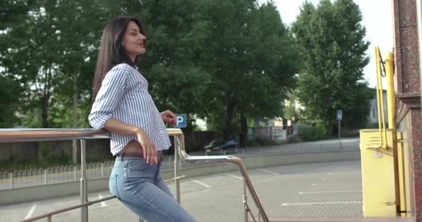 Happy lady leaned on handrail, flirts with hair and shows finger into camera — Stock Video