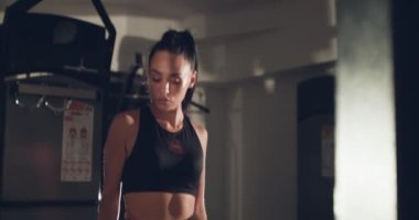 Ciddi bayan sporcu spor salonunda antrenman yapmak için spor ipine bakar.