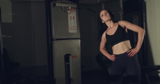 Pretty girl makes tilts of the torso to the sides in a gym — Stock Video