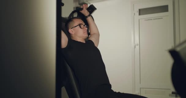 Спортсмен в окулярах працює з симулятором для перекачування м'язів грудей у спортзалі — стокове відео