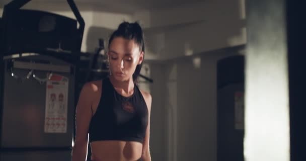 Athlète féminine sérieuse tient et regarde sur une corde de sport pour l'entraînement dans une salle de gym — Video