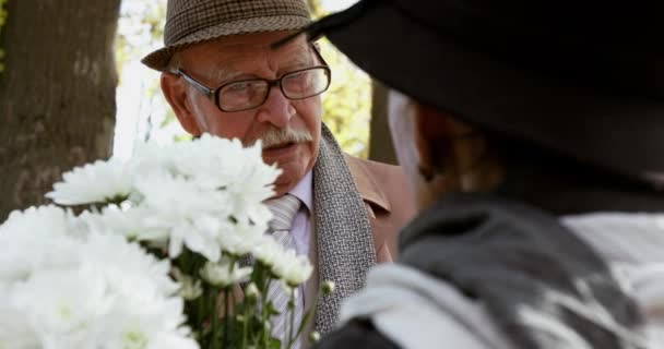 Portret uroczej pary starców z bukietem kwiatów rozmowy na romantyczne spotkanie — Wideo stockowe
