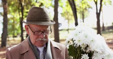 Yakın, zarif, elinde bir buket çiçekle romantik bir şekilde parkta yürüyor.