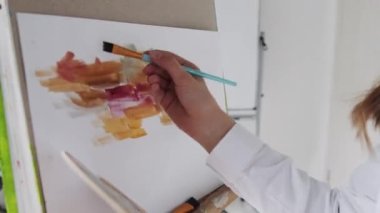 Kapalı alanda, ahşap ellerin, boya fırçası ve palet ile resim çizdiği, renkli boyalar..