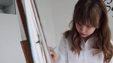 Easel 'de çocuk resimleri, atölye sınıfında okul çocuğu. Sınıfta Sanat Sanatında Çalışan Genç Kız