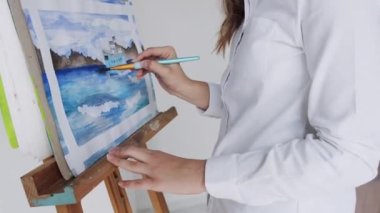 Sanat stüdyosunda resim yapan genç bir kadın sanatçı.