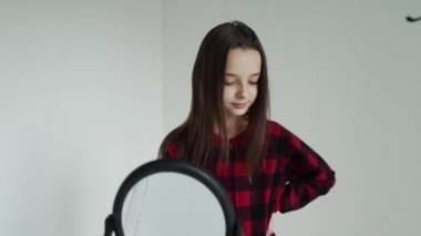 Kız aynada saçlarını tarıyor.