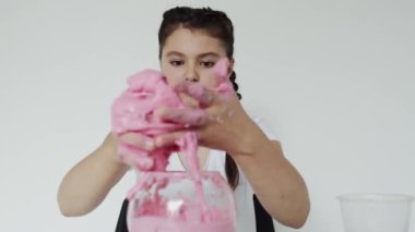 Ellerine pembe balçık süren bir kızın yakın görüntüsü.
