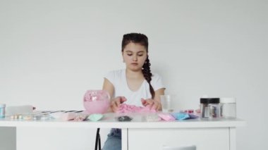 Kız masadaki elastik sümüğünü karıştırıyor.