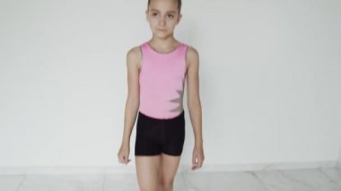 Okul çocuğu pembe ve siyah spor kıyafetleriyle yürüyor.