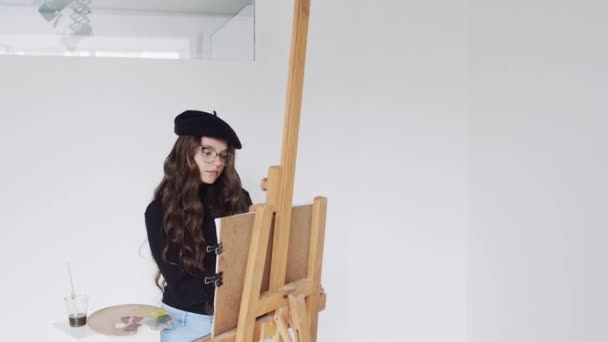 Joven artista en boina pintura cuadro sobre lienzo en estudio de arte — Vídeos de Stock