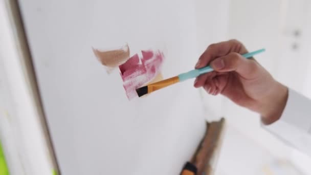 Κοντινό πλάνο των χεριών wooman σχέδιο εικόνα με πινέλο και παλέτα με πολύχρωμα χρώματα σε easel εσωτερικούς χώρους. — Αρχείο Βίντεο
