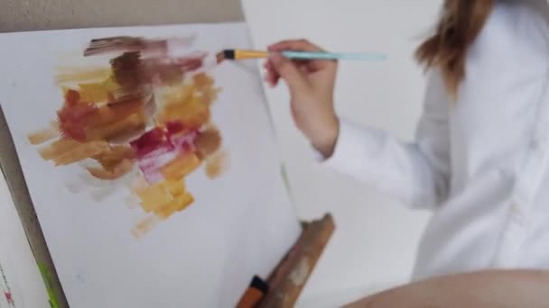 Κοντινό πλάνο των χεριών wooman σχέδιο εικόνα με πινέλο και παλέτα με πολύχρωμα χρώματα σε easel εσωτερικούς χώρους. — Αρχείο Βίντεο