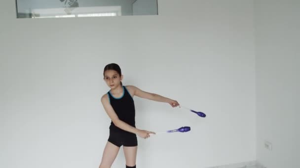 Дівчина в спортивному одязі робить кола з гімнастичними метами — стокове відео