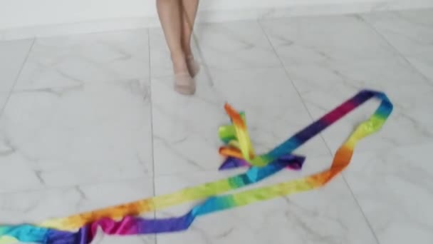 Pretty young girl with coloured ribbon on white floor — Video Stock