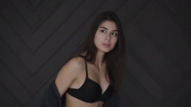 Siyah iç çamaşırlı baştan çıkarıcı esmer stüdyoda sandalyede oturuyor.