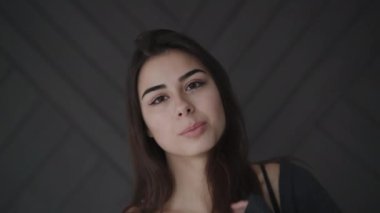 Siyah iç çamaşırlı tutkulu esmerin portresi kameraya gülümsüyor.