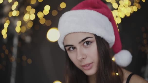 Atractiva chica de ojos marrones reflexivo en sombrero rojo mira a la cámara en el interior — Vídeos de Stock