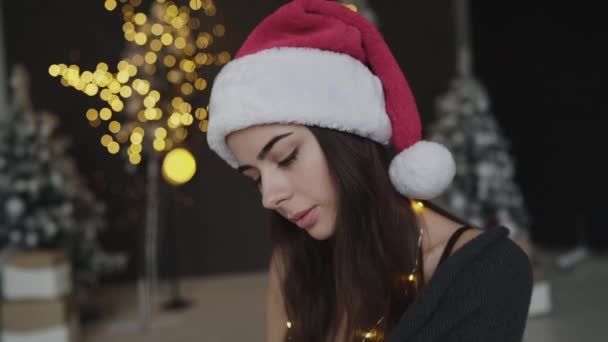Gorąca brunetka w nowym roku kapelusz i bielizna starannie patrzy w aparat — Wideo stockowe