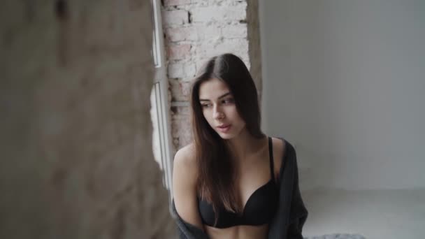 Portrait of admiring girl in lingerie relaxes at window in light raw building — Vídeo de Stock