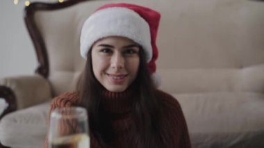 Kırmızı şapkalı güzel kızın portresi elinde bir bardak şampanya ve gülümseme.