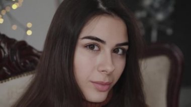 Güzel bir kızın portresi poz verir ve odadaki lüks koltukta kameraya bakar.
