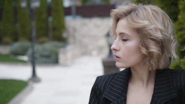 Sevimli, ciddi bir kadının portresi kameraya açık havada gülümseyerek bakıyor.