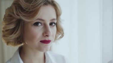 Odadaki ışık penceresinde kameraya gülümseyen mutlu kadının portresi.