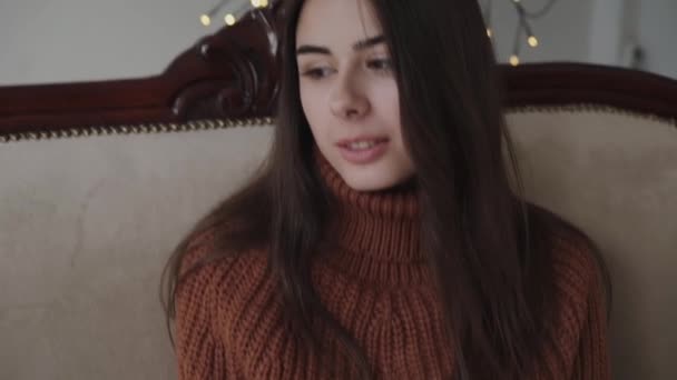 Portré aranyos lány pulóver pózol luxus kanapé a szobában — Stock videók
