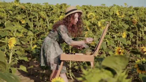 Curly-haired lady painting with watercolors among colourful sunflowers — Vídeos de Stock