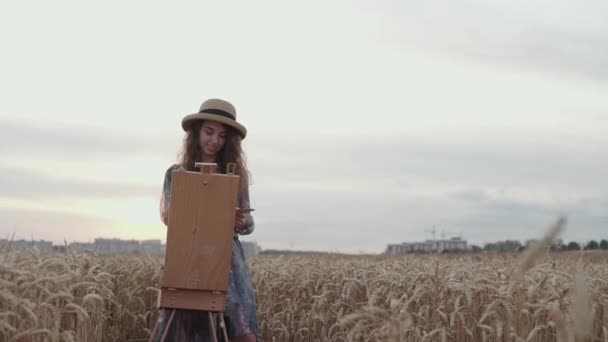 Joyeux peintre souriant et peignant sur toile parmi le champ de blé mûr spacieux — Video