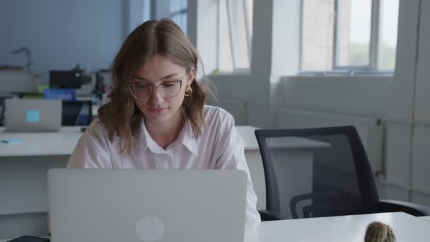 Business woman slowly typing on her lapton, slightly smiling — Stockvideo