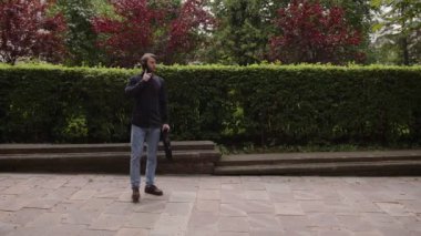 Adam sokakta yürüyor, telefonla konuşuyor ve bir buluşma ayarlıyor.