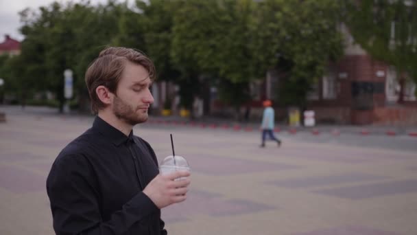 Een man loopt naar het centrum drinkt koffie en geniet van het leven — Stockvideo