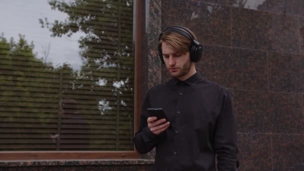 Muž ve sluchátkách píše poslovi. — Stock video