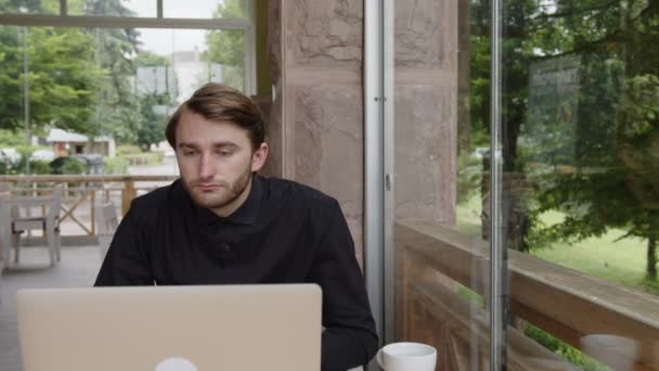 A man works on the Internet on a gray laptop — Vídeo de Stock