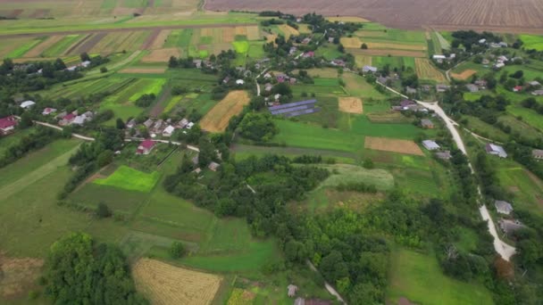 Letecký pohled z letu nad typickou starou vesnicí s poli, solární stanicí a silnicí v letním období — Stock video