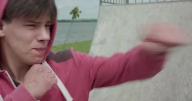 Kickboksör, rüzgarlı bir günde sahada kameraya yumruk atar.