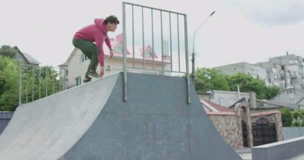Вид паркура спортсмена, делающего экстремальные перевороты на городской скейтборд-трек и сидящего — стоковое видео