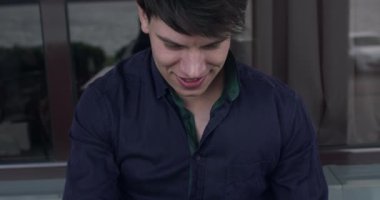 Saç stili sakso çeken neşeli bir adam, kafede görüntülü sohbet sırasında çok güler.