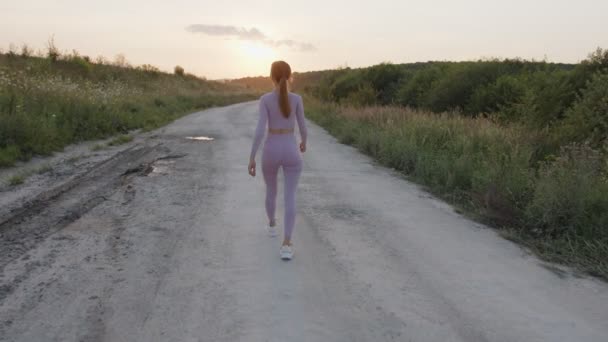 Zadní pohled na mladou dívku, která kráčí po silnici — Stock video