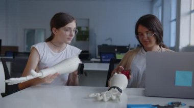 Kızlar dizüstü bilgisayarın ekranına bakın ve 3D yazdırılmış eli bağlayın