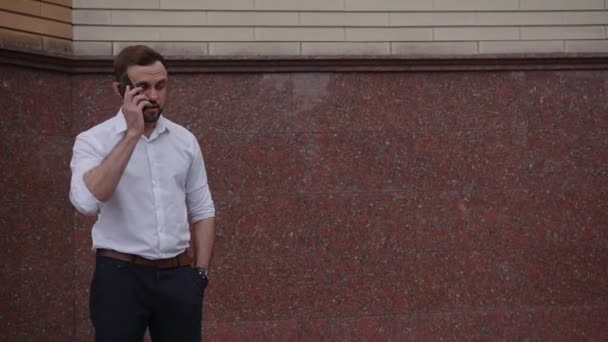 Homem atraente fala o seu telefone preto — Vídeo de Stock