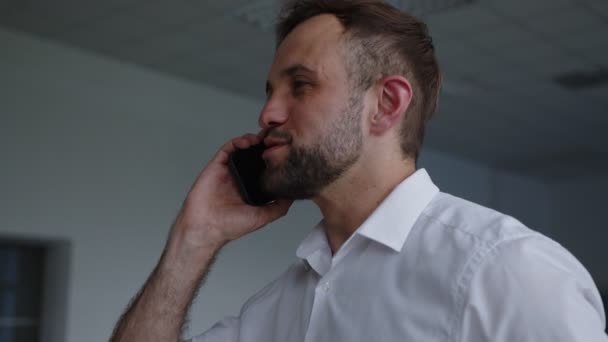 Sorriu homem com telefone preto fala sobre ele — Vídeo de Stock