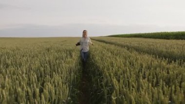 Buğday tarlasında koşan güzel bir kızın ağır çekimde